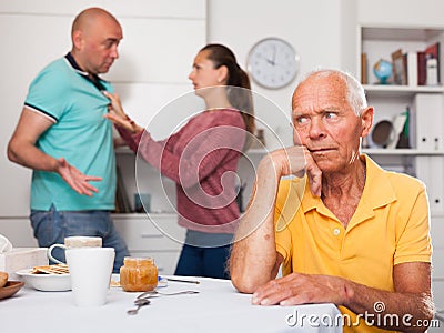 Elderly man sitting at table, unhappy family couple quarrelling Stock Photo