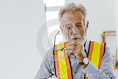 An elderly man worker removed glasses because of eyes irritation or stress from hard working Stock Photo