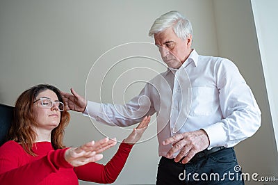 An elderly man hypnotizes a female patient. A woman in a session with a male hypnotherapist during a session. Therapist Stock Photo