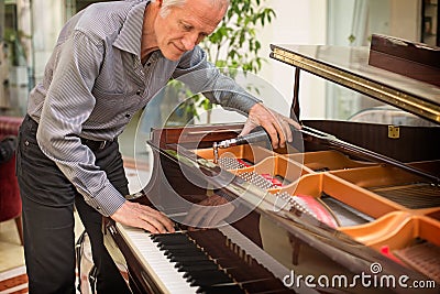 Elderly music instrument technician tuning a piano keyboard. Stock Photo