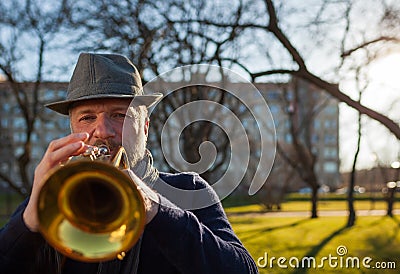 An elderly musician plays in the street on a trumpet Stock Photo