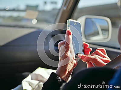 Elderly passenger in car looking at smart phone on the road for navigation while driving. Stock Photo