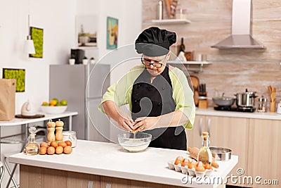 Elderly pastry chef cracking egg Stock Photo