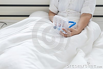 Elderly patient using incentive spirometer or three balls for stimulate lungs in bedroom Stock Photo