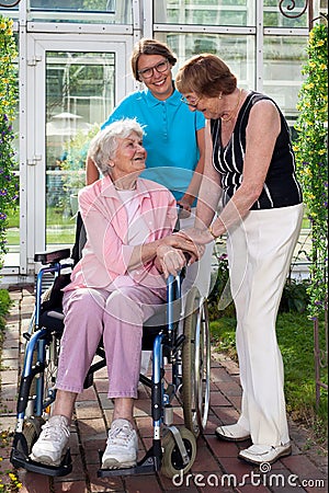 Elderly Patient on Wheel Chair with Two Caregivers. Stock Photo