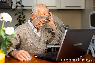 desperate old man pensioner chatting online via laptop with friends at home Stock Photo