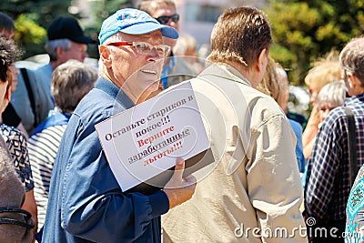 An elderly pensioner with a poster for a rally. Text in Russian: Leave the old people alone, Return the earned benefits Editorial Stock Photo