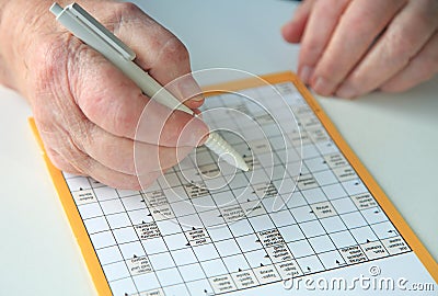 Elderly person doing crossword puzzle Stock Photo