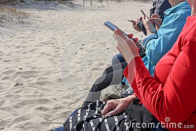 Elderly persons sitting on a bench at the seaside and use smartphones Stock Photo