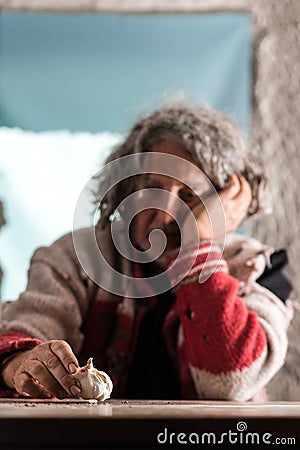 Elderly poor man with dirty hands sitting holding a garlic bulb Stock Photo