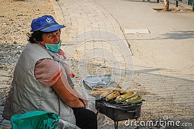 An elderly poor woman sells fried corn on the street of the capital of Albania - Tirana Editorial Stock Photo