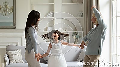 Grandmother adult daughter and granddaughter dancing in modern living room Stock Photo