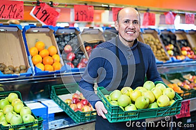 Elderly seller offering seasonal ripe fruits in local grocery Stock Photo