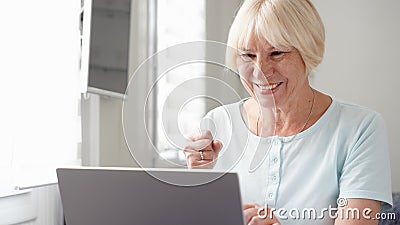 Elderly senior blond woman working on laptop computer at home. Received good news excited and happy Stock Photo