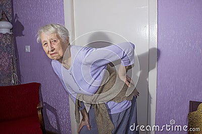 Elderly senior 75s woman with painful feelings in lumbar, massaging low back to reduce ache, suffer from backache discomfort Stock Photo