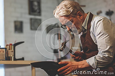 An elderly shoemaker in uniform at work Stock Photo