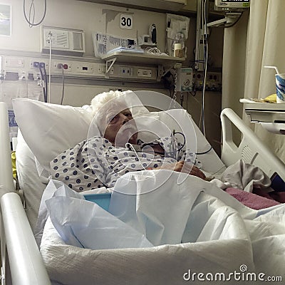 Elderly, white haired male patient in hospital bed Stock Photo