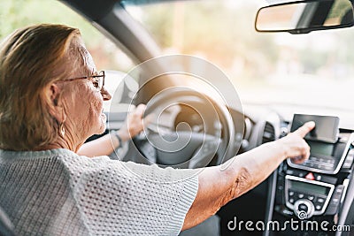 Elderly woman behind the steering wheel using her satnav Stock Photo