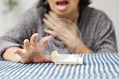 Elderly woman choking and holding an asthma spray Stock Photo