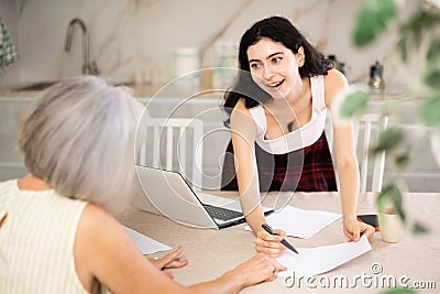 Elderly woman discussing deal with saleswoman in kitchen Stock Photo