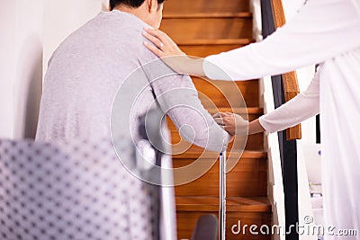 Elderly woman hands holding sticks while walking up stair at home,Caregiving take care and support,Self-Care for Family Caregivers Stock Photo