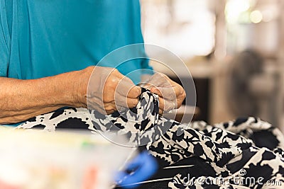 Elderly woman hands using needle and thread to mend a dress. Stock Photo