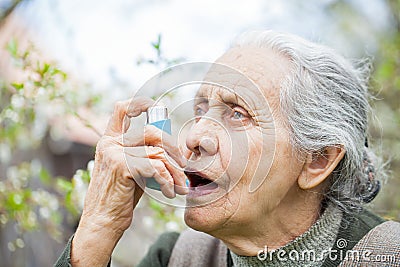 Elderly woman having asthma attack, holding a bronchodilator Stock Photo