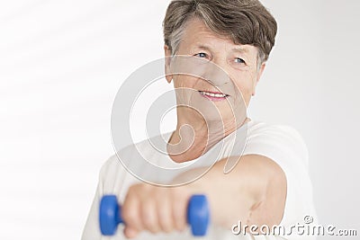 Elderly woman holding blue dumbbell Stock Photo