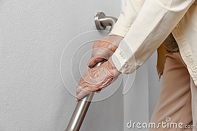 Elderly woman holding on handrail for safety walk steps Stock Photo