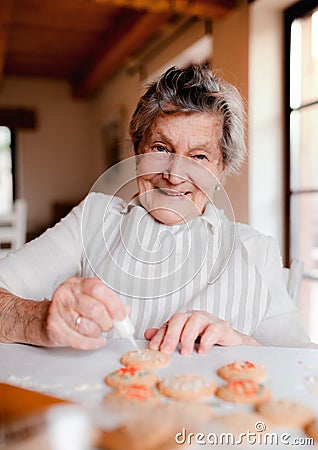 Elderly woman making and decorating cakes in a kitchen at home. Stock Photo