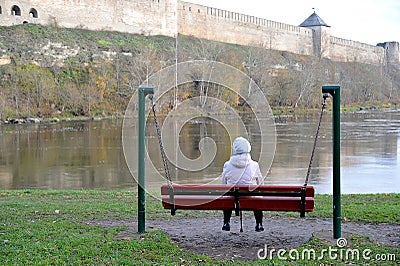 An elderly woman pensioner sitting on a bench and looking at the Editorial Stock Photo