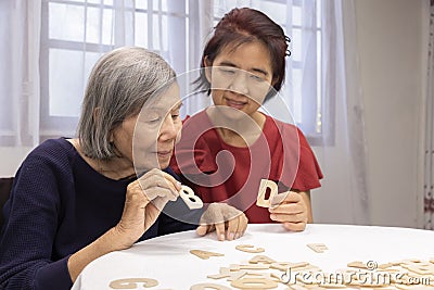 Elderly woman playing alphabet games for improve mental health and memory with daughter Stock Photo