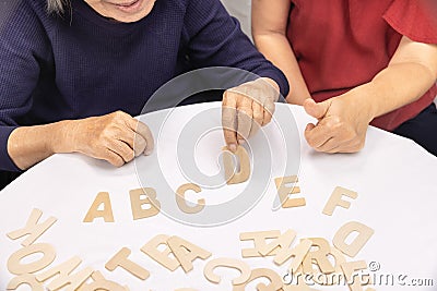 Elderly woman playing alphabet games for improve mental health and memory with daughter Stock Photo