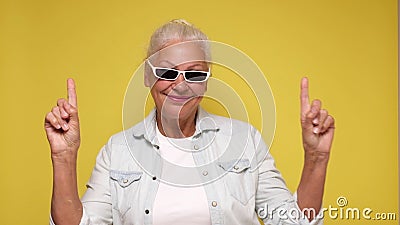 An elderly woman points her finger to attract attention on a beige background Stock Photo