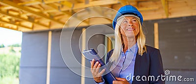 Elderly woman with protective helmet working as an architect doing expertise at construction of ecological renewable low Stock Photo