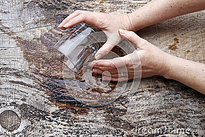 An elderly woman`s hands shake so badly that she spills a glass of water Stock Photo