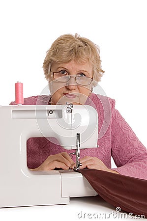 The elderly woman sews on the sewing machine Stock Photo