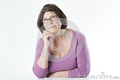 Elderly woman sitting at the table, leaning on her hand. Stock Photo