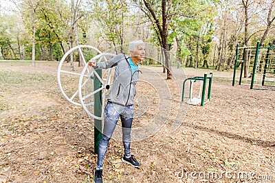 Elderly Woman In Sports Clothes Exercising At Outdoor Fitness Park Stock Photo