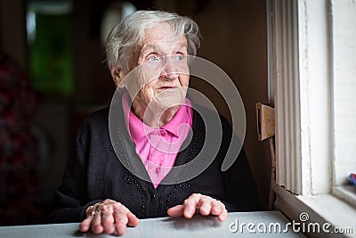 Elderly woman surprised stares out of the window. Happy. Stock Photo