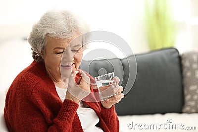 Elderly woman taking pill at home Stock Photo