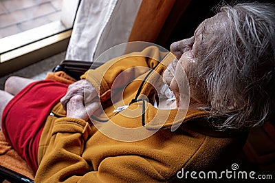 Elderly woman in a wheelchair looking out the window Stock Photo