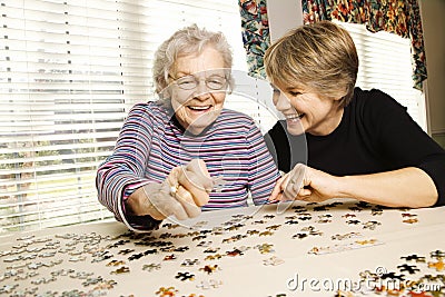 Elderly Woman and Younger Woman Doing Puzzle Stock Photo