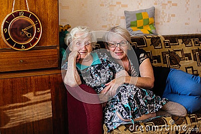 Elderly woman in his home sitting on the couch with adult daughter. Family. Stock Photo
