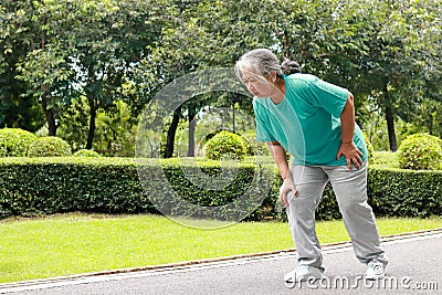 Elderly women jogging in the park She has pain in her right knee. Stock Photo