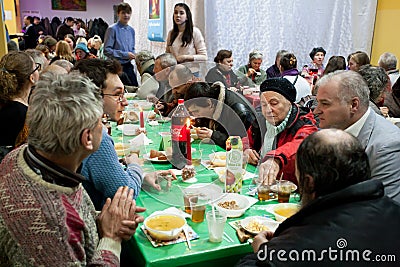 Elderly women and men have a food at the Christmas charity dinner for the homeless Editorial Stock Photo