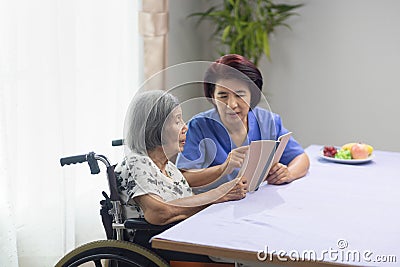 Elderly woman reading aloud a book for dementia therapy with caregiver Stock Photo