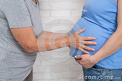 An elderly woman touches the belly of her pregnant daughter. Close-up. Stock Photo