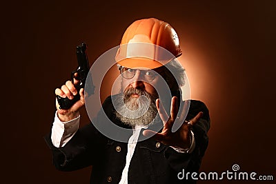 An elderly worker in a helmet gestures warning signs, studio portrait Stock Photo