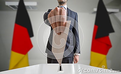 Election or referendum in Germany. Voter holds envelope in hand above ballot. German flags in background Stock Photo